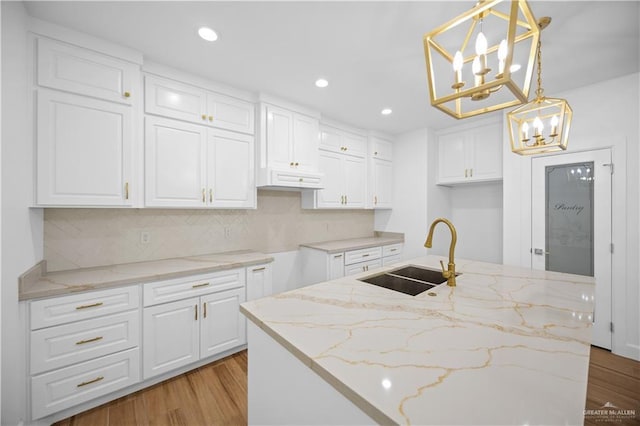 556 Demi St, Edinburg, TX 78542 - kitchen with a sink, light wood finished floors, light stone countertops, and a notable chandelier