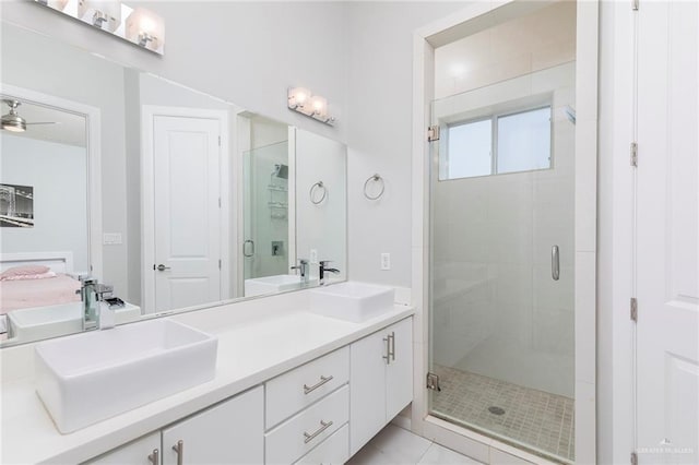 bathroom featuring double vanity, ceiling fan, a sink, and a stall shower