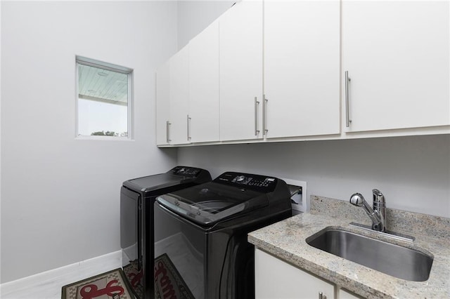 washroom featuring washer and dryer, baseboards, a sink, and cabinet space