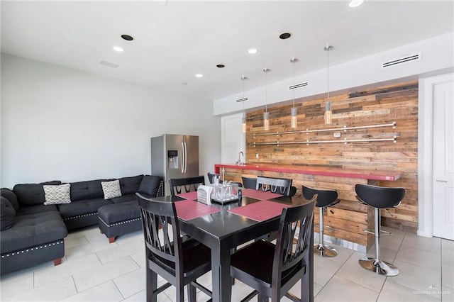 dining room with wooden walls, light tile patterned floors, recessed lighting, and visible vents