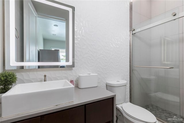 full bathroom featuring vanity, a textured wall, a stall shower, and toilet