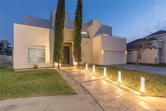 modern home with a garage, a front lawn, stucco siding, and concrete driveway