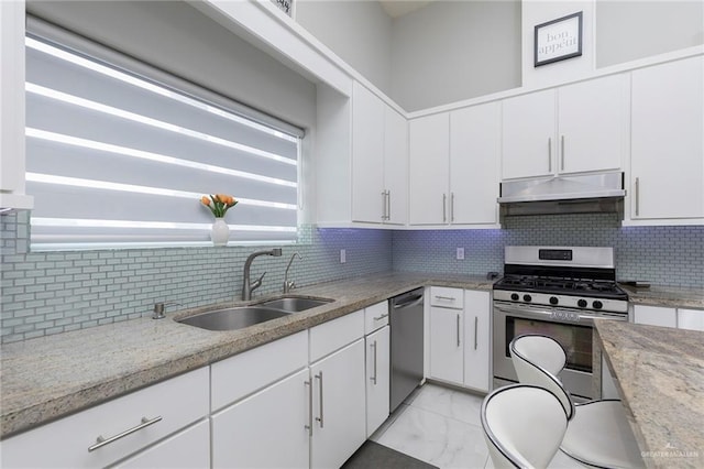 kitchen featuring white cabinetry, under cabinet range hood, a sink, appliances with stainless steel finishes, and backsplash