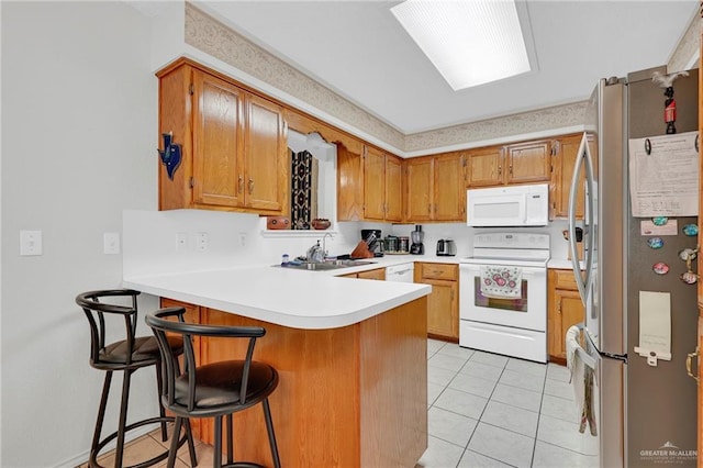 1700 Aries St, Mission, TX 78572 - kitchen with white appliances, a peninsula, light tile patterned floors, light countertops, and a kitchen breakfast bar