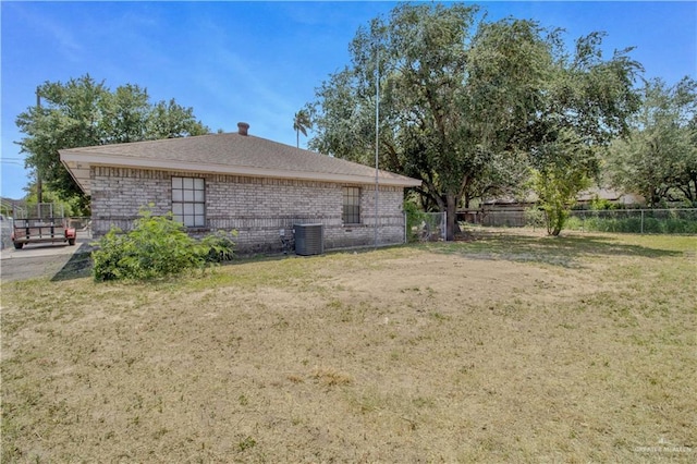 view of home's exterior featuring brick siding, fence, a yard, and cooling unit
