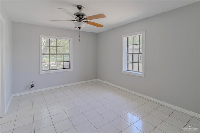 empty room with a ceiling fan, baseboards, and light tile patterned floors