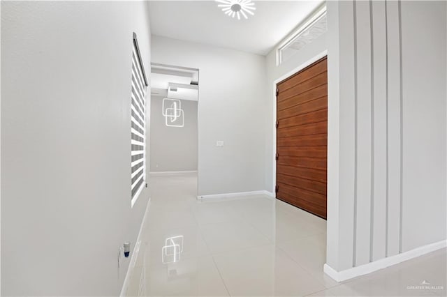 corridor featuring light tile patterned flooring and baseboards