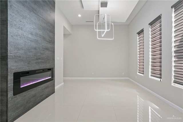 unfurnished dining area with tile patterned floors, recessed lighting, a glass covered fireplace, and baseboards