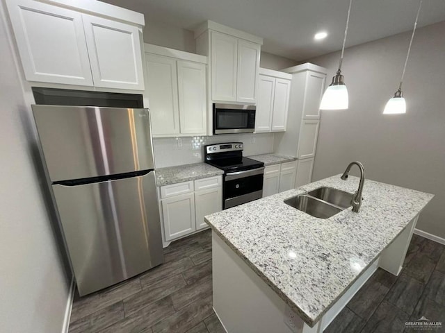 kitchen with appliances with stainless steel finishes, a center island with sink, white cabinetry, and sink