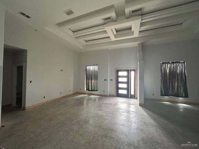 interior space with beamed ceiling, coffered ceiling, a towering ceiling, and concrete floors