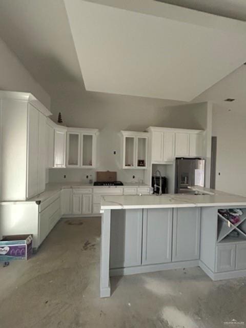 kitchen with fridge with ice dispenser, a spacious island, and white cabinets