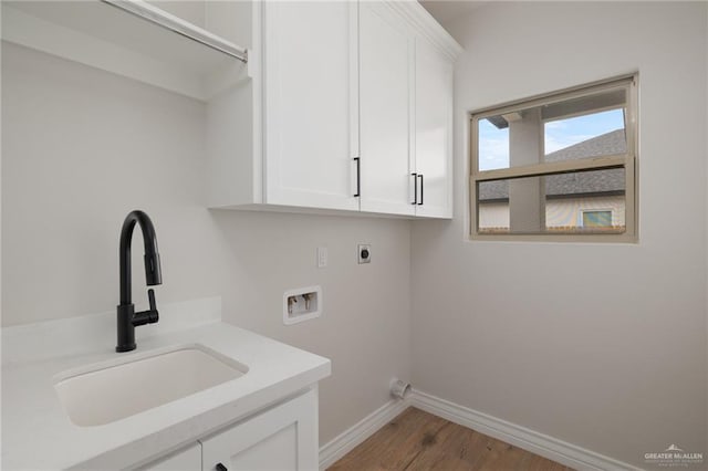 washroom with wood-type flooring, sink, cabinets, hookup for a washing machine, and electric dryer hookup