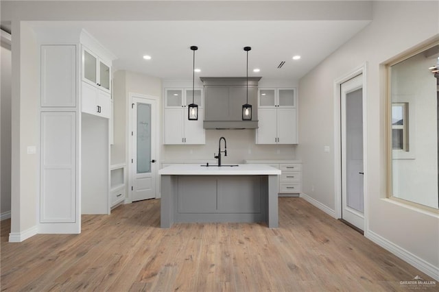 kitchen with pendant lighting, sink, gray cabinetry, a center island with sink, and light wood-type flooring