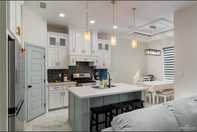 kitchen featuring white cabinets, appliances with stainless steel finishes, a breakfast bar, and tasteful backsplash