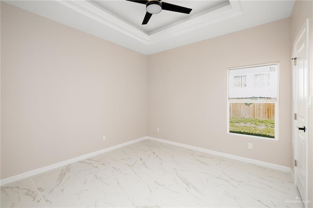 empty room featuring a tray ceiling and ceiling fan