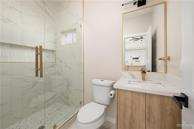 bathroom featuring vanity, toilet, ceiling fan, and a shower with shower door