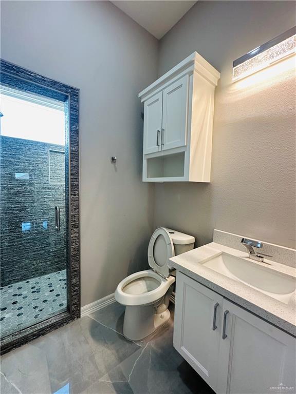 bathroom featuring vanity, toilet, and a shower with shower door