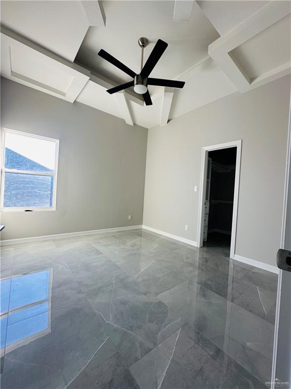 unfurnished room featuring ceiling fan, coffered ceiling, and beam ceiling