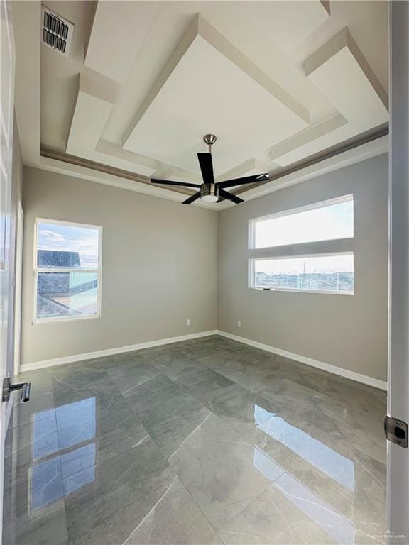 unfurnished room with a raised ceiling, a healthy amount of sunlight, and ceiling fan