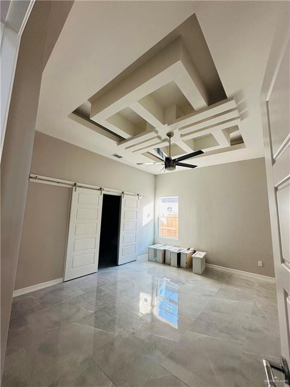 unfurnished bedroom with beamed ceiling, a barn door, coffered ceiling, and ceiling fan