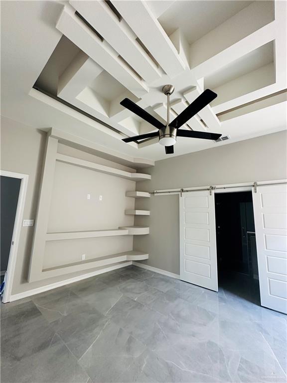 unfurnished bedroom featuring a barn door and ceiling fan