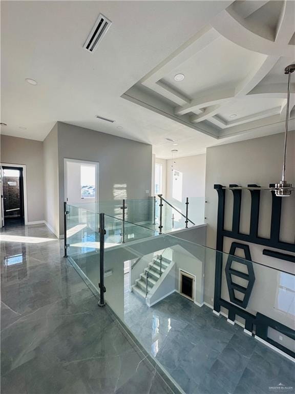 stairway featuring coffered ceiling and a healthy amount of sunlight