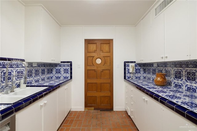 kitchen with white cabinetry, sink, and backsplash