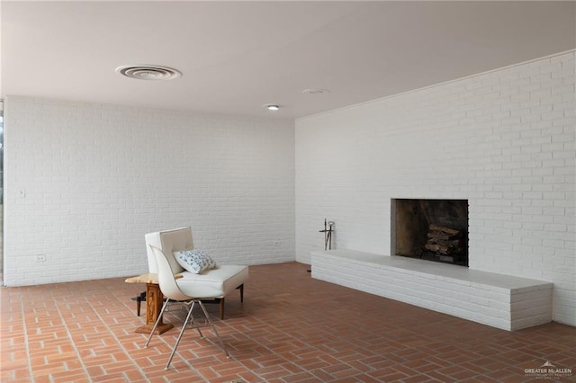 living area with a brick fireplace and brick wall