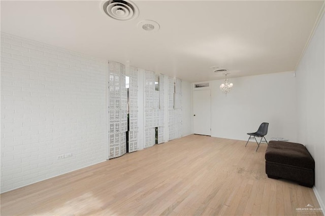 sitting room featuring hardwood / wood-style flooring, brick wall, and a chandelier