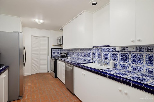 kitchen featuring stainless steel appliances, tile countertops, and white cabinetry