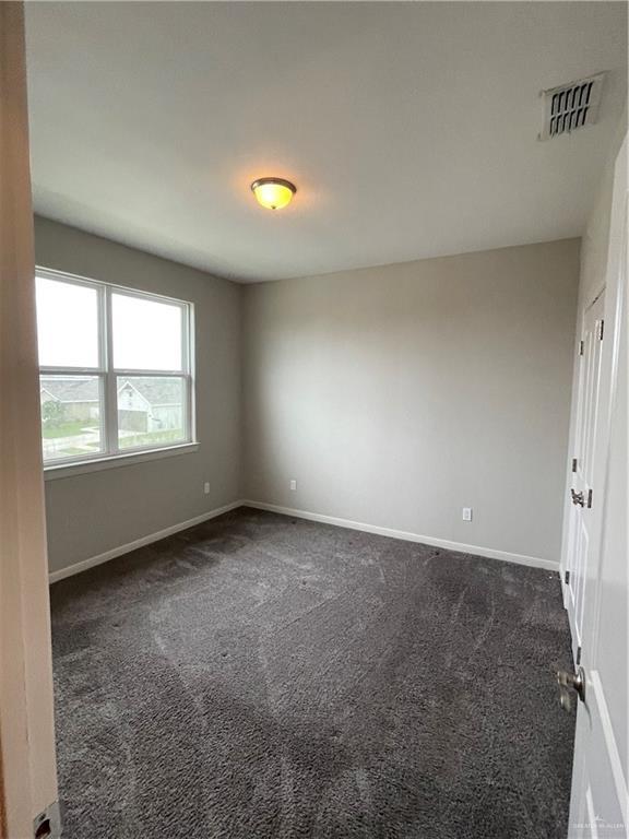unfurnished room featuring dark colored carpet