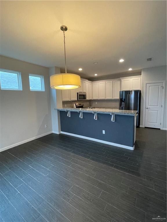kitchen with black fridge, white cabinets, a kitchen bar, decorative light fixtures, and kitchen peninsula
