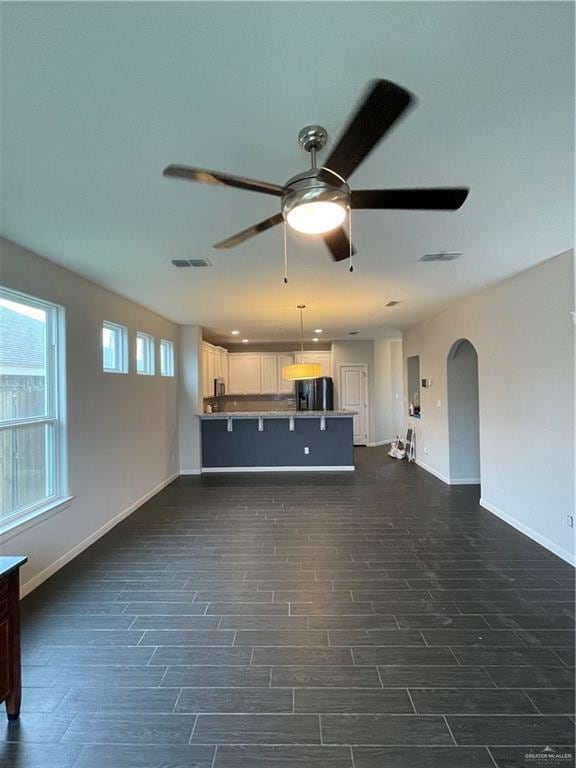 unfurnished living room featuring ceiling fan and dark hardwood / wood-style flooring