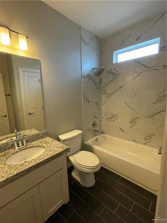 full bathroom featuring tiled shower / bath, vanity, and toilet
