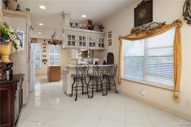 912 Bentsen Rd, Mcallen, TX 78501 - kitchen featuring a kitchen bar, a peninsula, glass insert cabinets, recessed lighting, and light tile patterned flooring