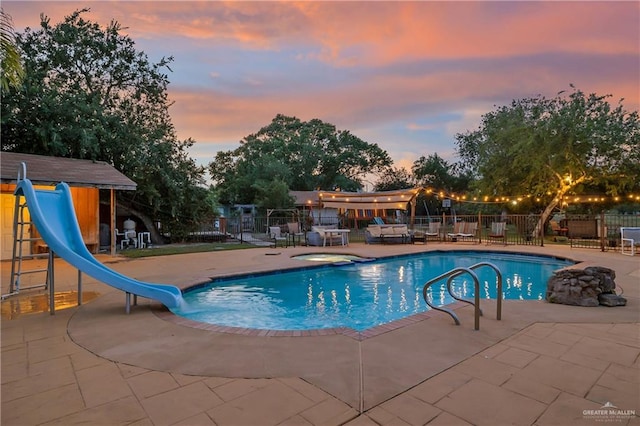 912 Bentsen Rd, Mcallen, TX 78501 - pool at dusk featuring a water slide, fence, a patio, and an in-ground hot tub