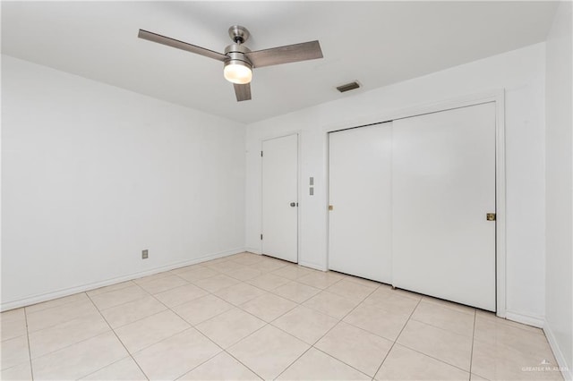unfurnished bedroom with light tile patterned floors, ceiling fan, and a closet