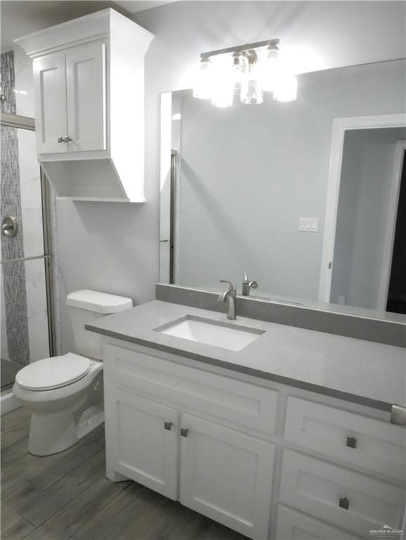 bathroom with wood-type flooring, vanity, toilet, and walk in shower