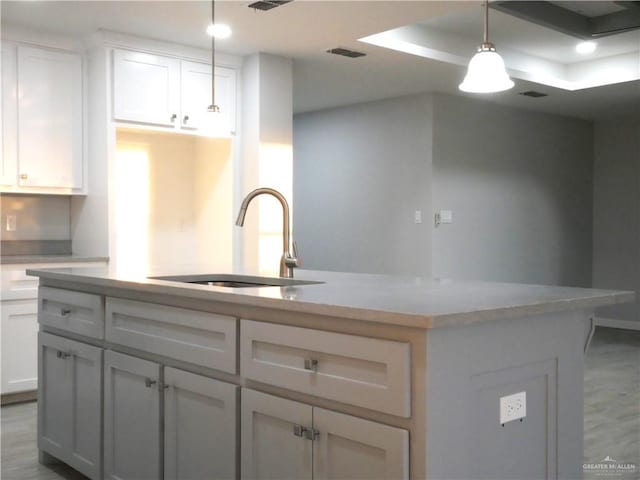 kitchen featuring a center island, white cabinetry, hanging light fixtures, and sink