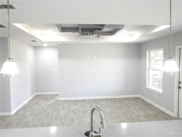 unfurnished room featuring a raised ceiling, ceiling fan, and light hardwood / wood-style floors