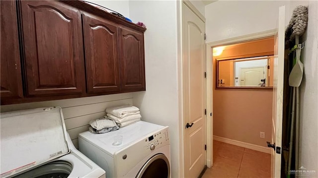 clothes washing area with cabinets, light tile patterned floors, and washer and clothes dryer