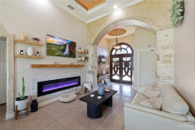 2112 Saginaw Ave, Edinburg, TX 78541 - tiled living area with arched walkways, a high ceiling, crown molding, and a glass covered fireplace