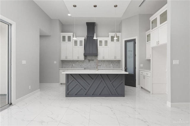 kitchen with decorative light fixtures, white cabinetry, an island with sink, and tasteful backsplash