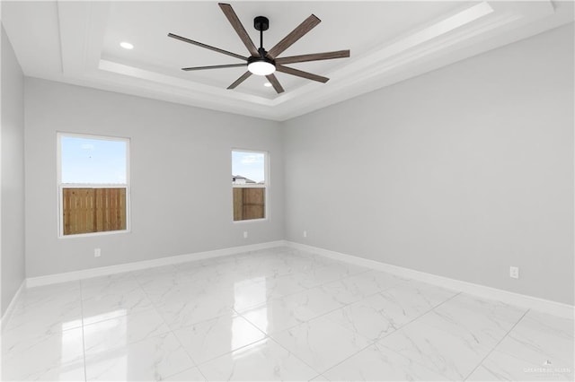 empty room featuring ceiling fan and a tray ceiling