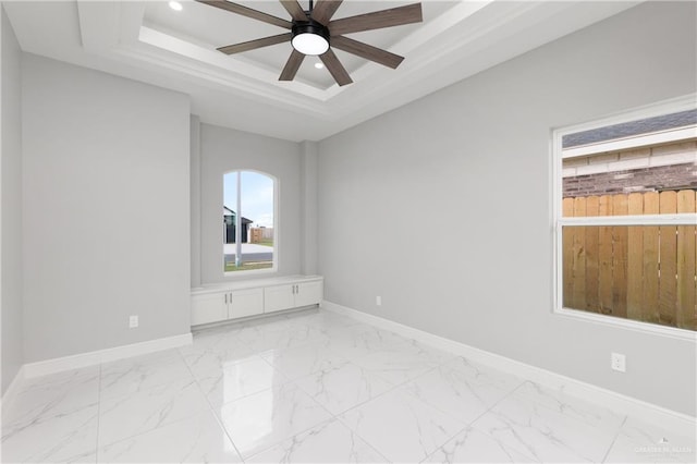 empty room featuring ceiling fan and a tray ceiling