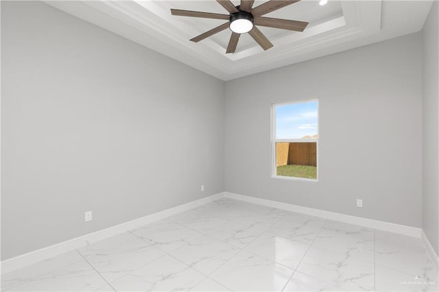 empty room featuring a tray ceiling and ceiling fan