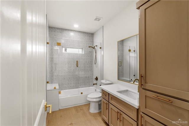 full bathroom with enclosed tub / shower combo, vanity, toilet, and hardwood / wood-style floors