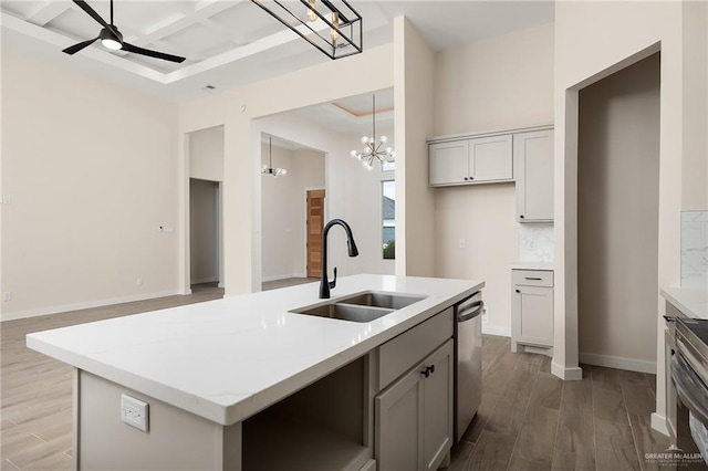 kitchen featuring stainless steel appliances, sink, hardwood / wood-style flooring, hanging light fixtures, and an island with sink