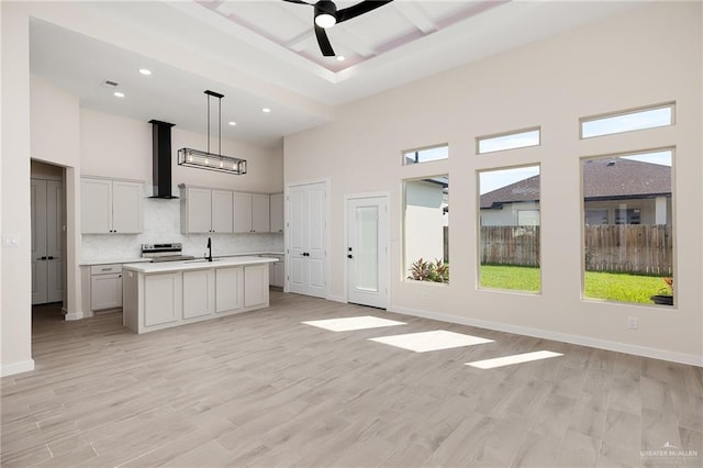 unfurnished living room featuring ceiling fan, a high ceiling, and light hardwood / wood-style flooring