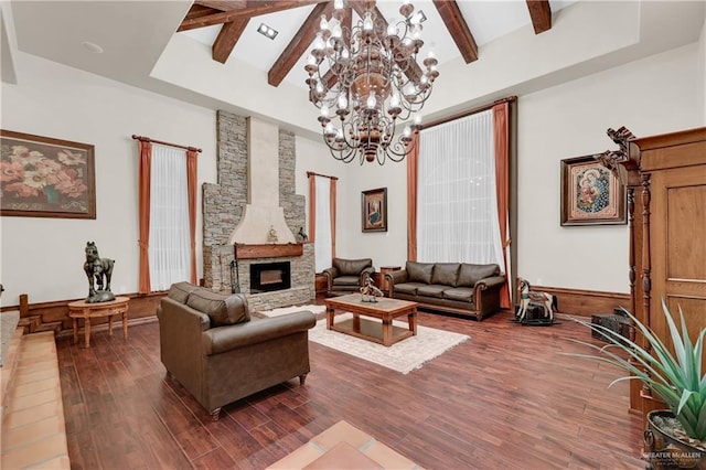 living room with a stone fireplace, beam ceiling, dark wood-type flooring, and an inviting chandelier